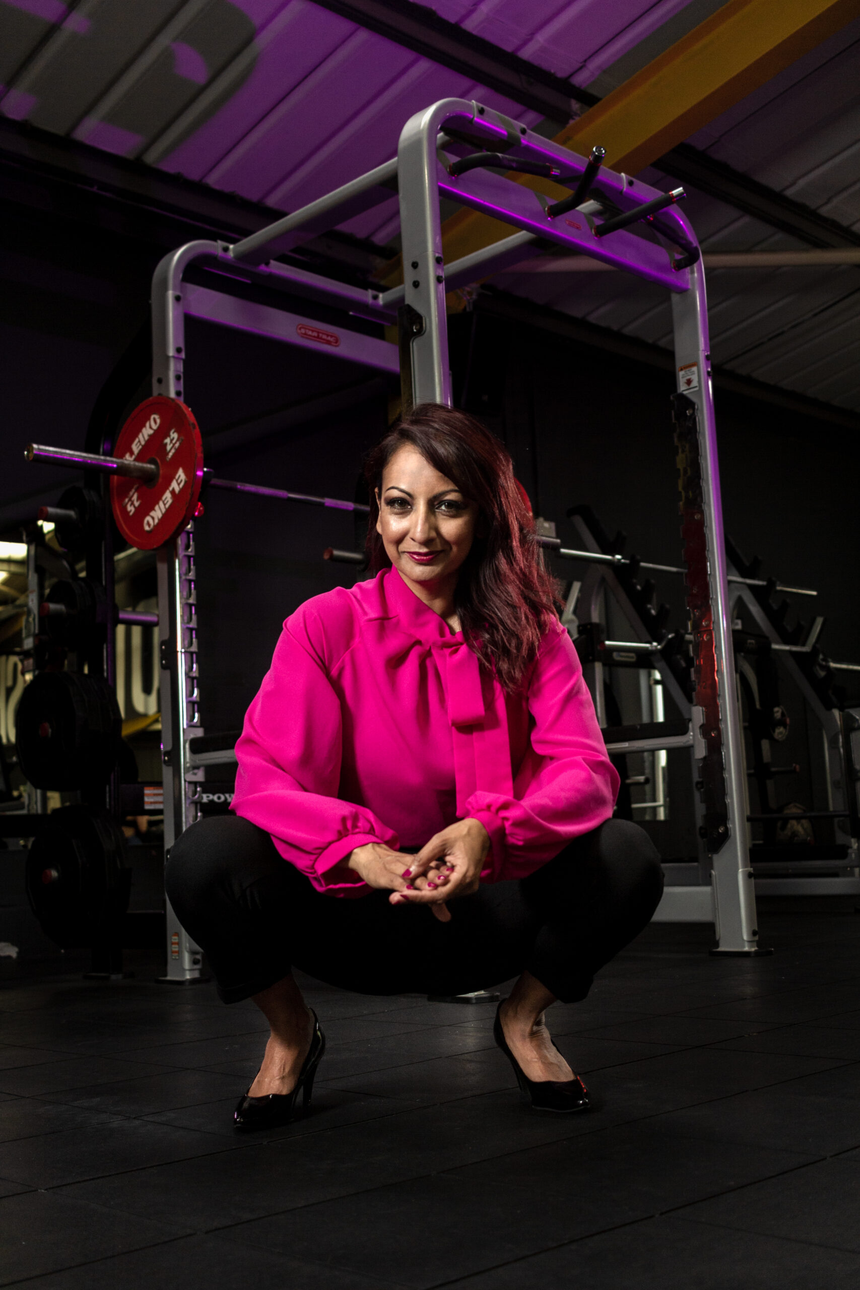 Aneela Rose Crouching During Gym Shoot Aneela Rose crouching beside a barbell during a strength focused gym shoot