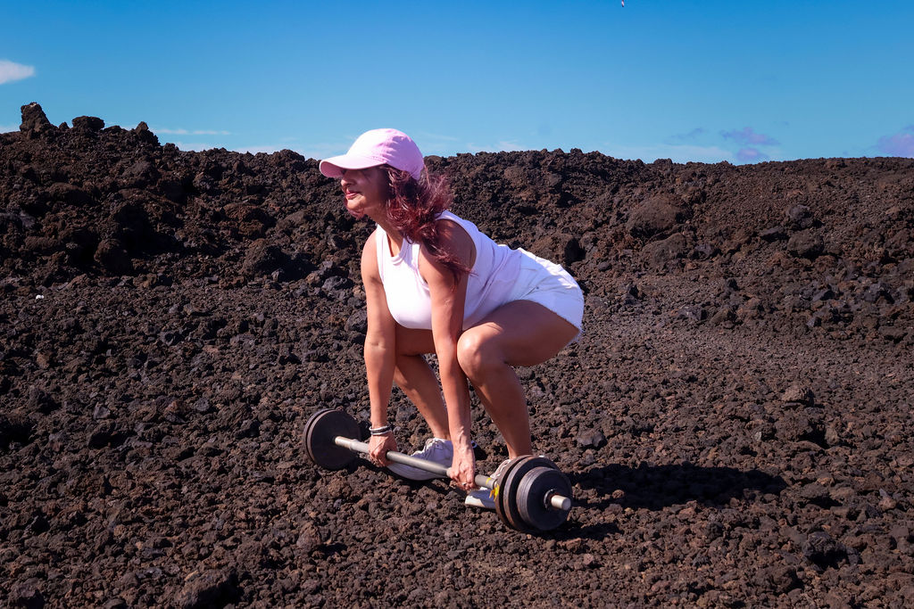 Aneela Rose Setting Up Desert Deadlift Aneela Rose setting her grip on a barbell on volcanic terrain in Lanzarote