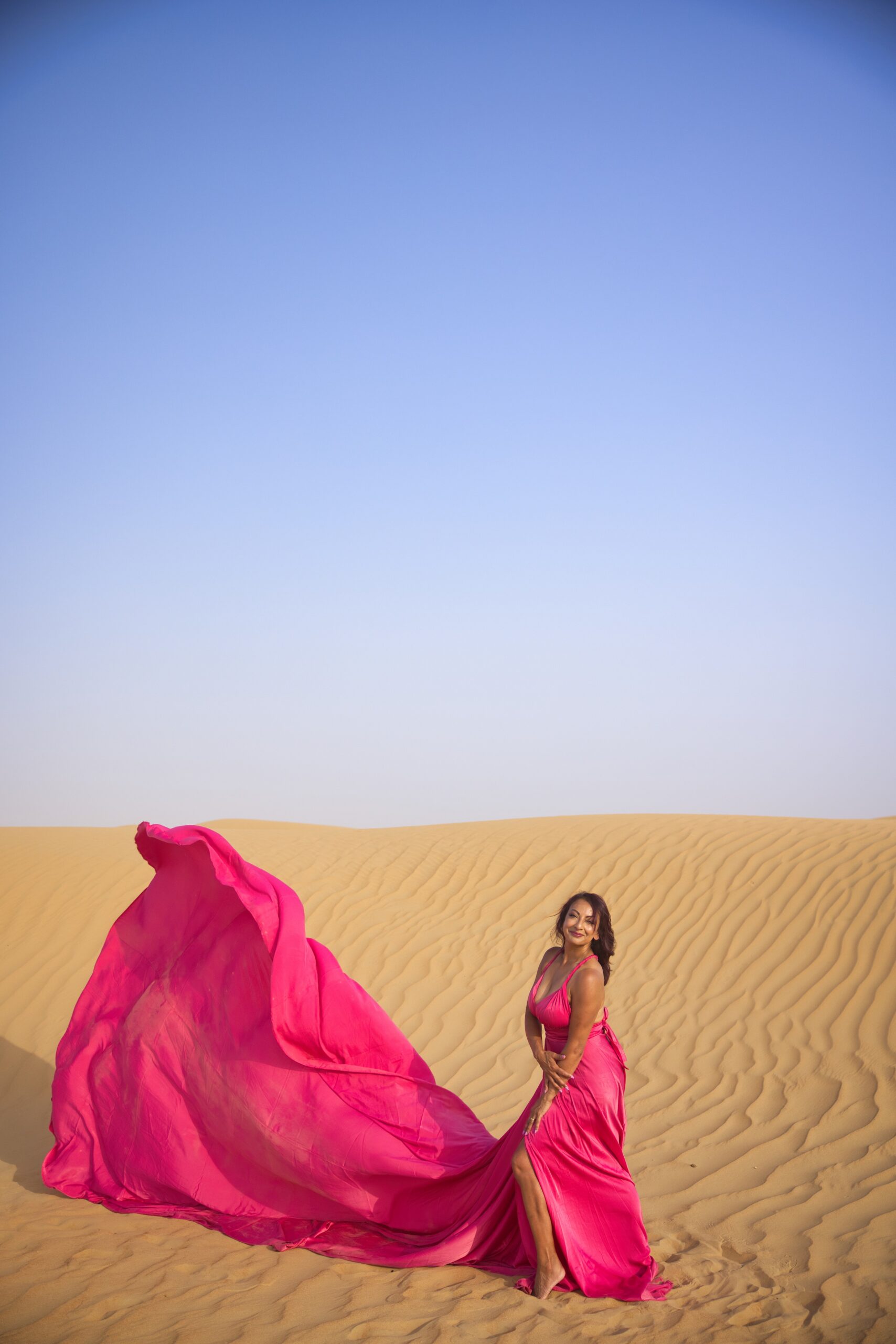 Aneela Rose Hot Pink Desert Portrait Aneela Rose posing in a flowing hot pink dress against desert dunes