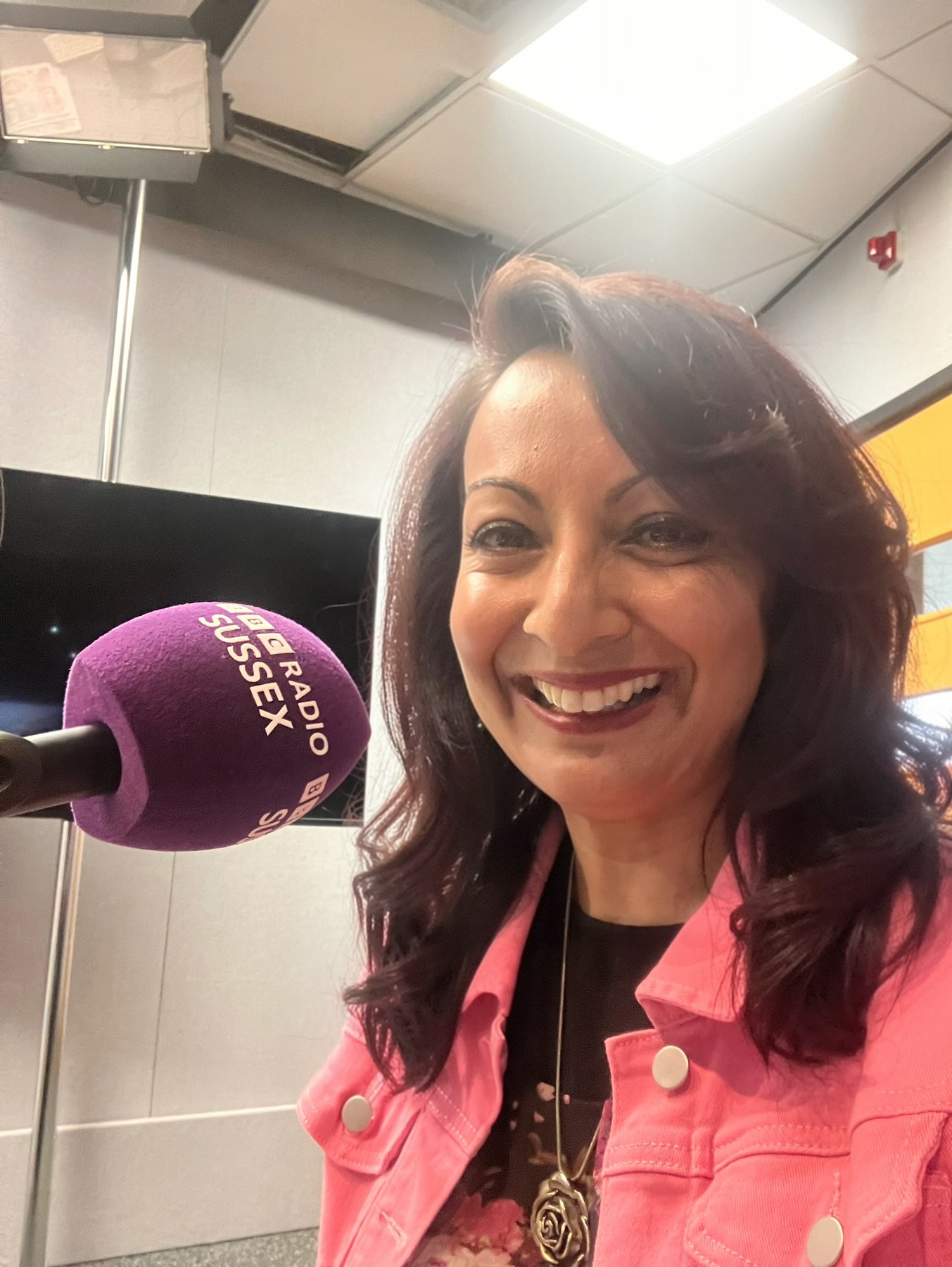 Aneela Rose at BBC Radio Sussex Aneela Rose smiling beside a BBC Radio Sussex microphone before her live lunchtime interview