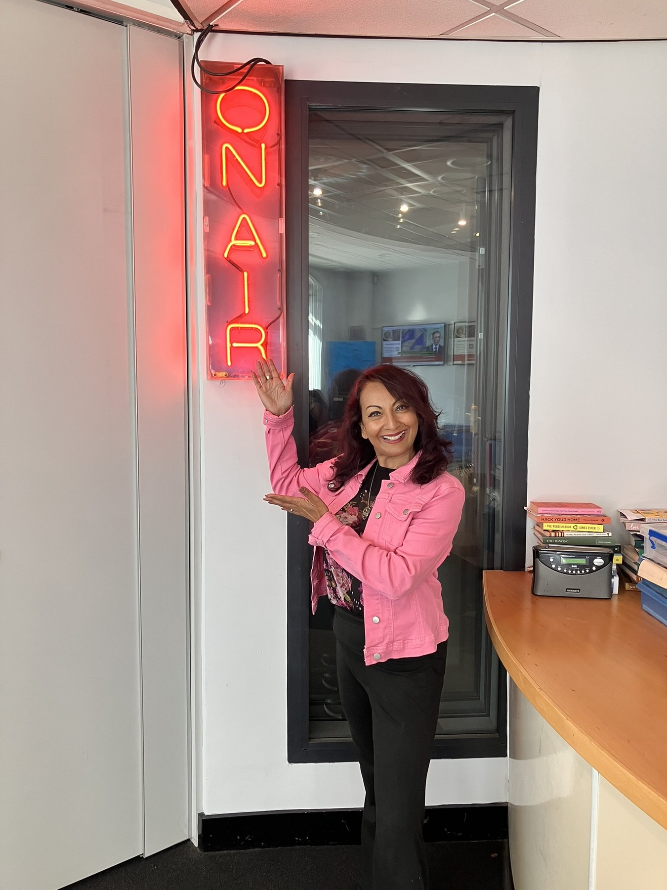 Aneela Rose at BBC Radio Sussex Studio Aneela Rose standing beside the on-air sign at BBC Radio Sussex in Brighton